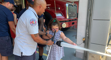 A young BELL participant checks out a running firehose with the help of the local firemen.